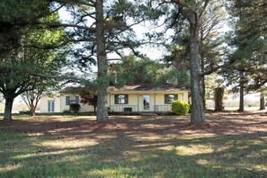 A single-story house with a front porch, surrounded by mature trees. - The Cozy Little Farmhouse (El Paso)
