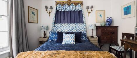 Un dormitorio con una cama grande, un aparador y una silla.