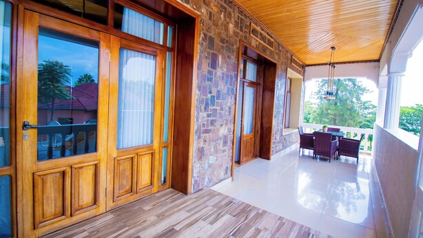 A spacious room with a wooden floor, large windows, and a balcony with outdoor furniture. - ArthillsBoutiqueHotel (Kigali)