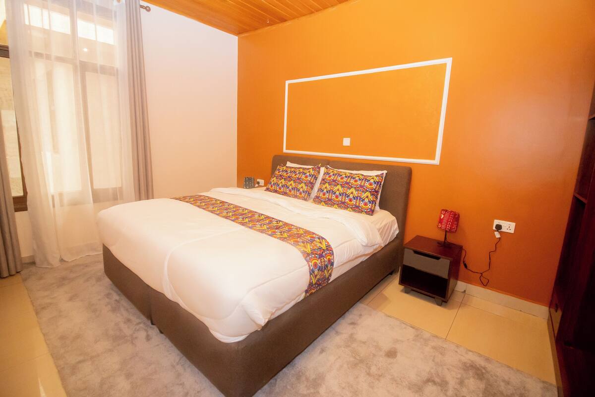 A bedroom with a bed, a bedside table, and a wall-mounted light fixture.