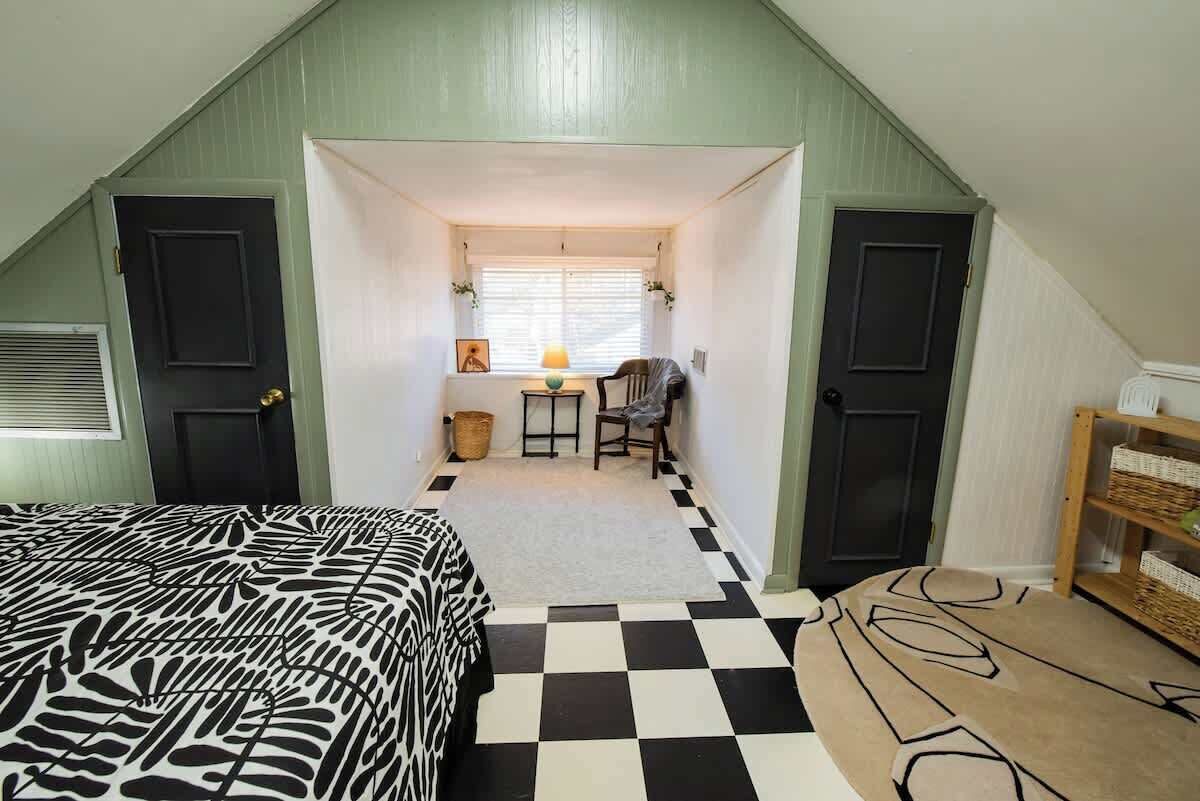 Ein Zimmer mit Schachbrettmuster-Boden, einem Bett mit Zebra-Muster-Bettwäsche, einem Schreibtisch mit Lampe und einem Sessel.