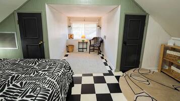 Ein Zimmer mit Schachbrettmuster-Boden, einem Bett mit Zebra-Muster-Bettwäsche, einem Schreibtisch mit Lampe und einem Sessel.