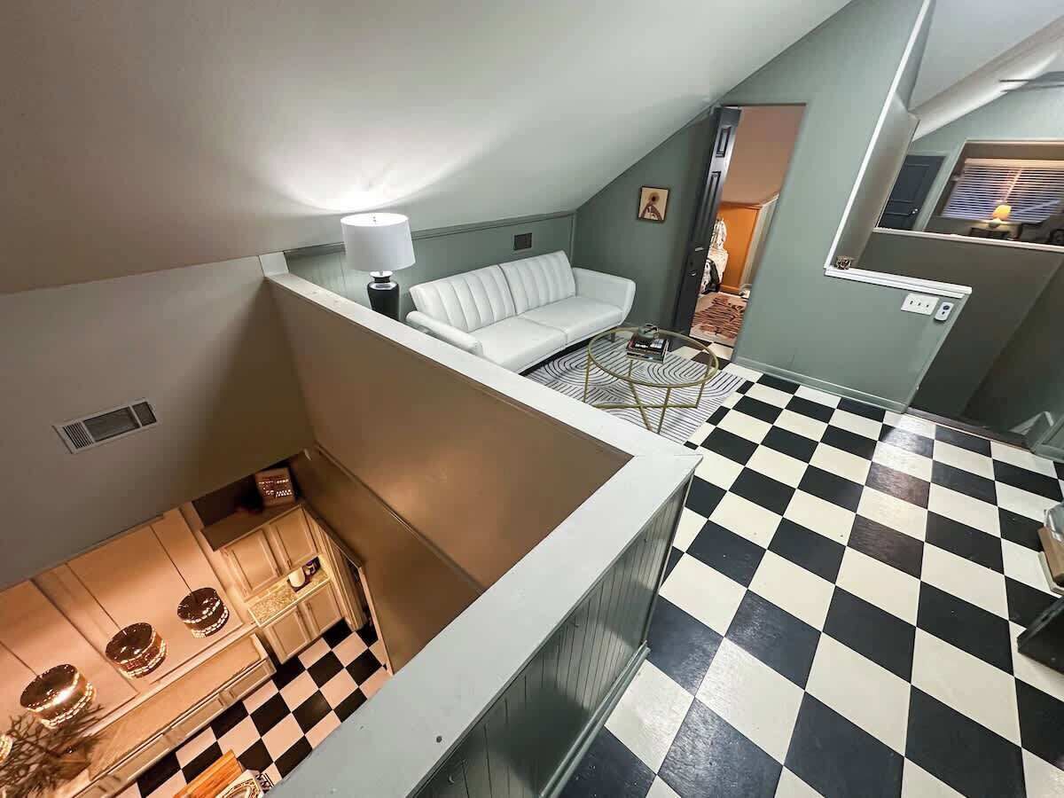 Une pièce avec un sol à carreaux, un canapé blanc et un coin repas comprenant une table et des chaises.