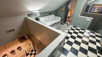 Une pièce avec un sol à carreaux, un canapé blanc et un coin repas comprenant une table et des chaises.
