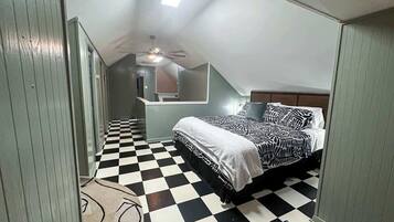 Une chambre avec un sol à carreaux, un lit avec une literie à motifs et un ventilateur de plafond.