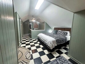 A bedroom with a checkered floor, a bed with patterned bedding, and a ceiling fan.