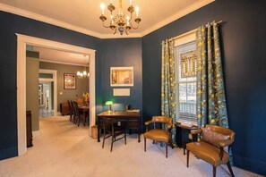 A room with a dining area, a desk, and a window with curtains.