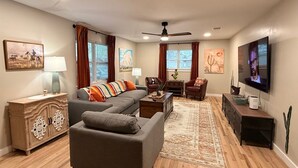 A living room with a sofa, armchairs, a coffee table, a TV, and a cabinet.