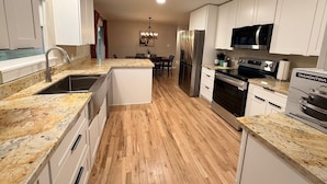 A modern kitchen with granite countertops, stainless steel appliances, and wooden flooring.