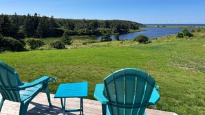 Een terras met twee stoelen en een kleine tafel met uitzicht op een meer en bos.