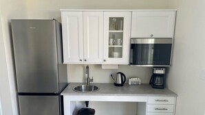 Een moderne keuken met een roestvrijstalen koelkast, een spoelbak, een koffiezetapparaat en een magnetron.