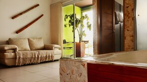 A living room with a sofa, a stone accent wall, a sliding glass door leading to a balcony, and a red cabinet. - HOTEL PORTOBELO GUATAPE (Guatapé)