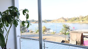 A balcony with a view of a river, a potted plant, and a metal railing. - HOTEL PORTOBELO GUATAPE (Guatapé)