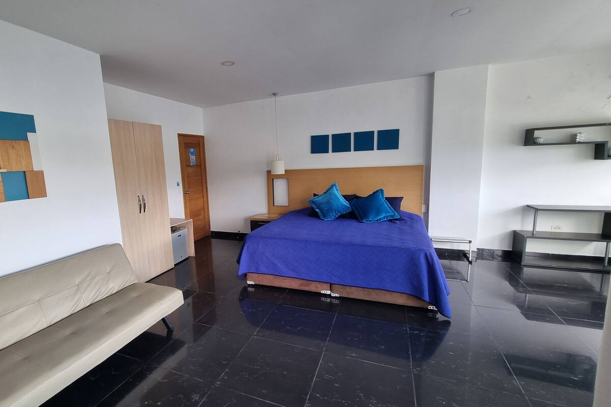 Ein modernes Hotelzimmer mit Bett, Sitzbank, Kleiderschrank und Schreibtisch.