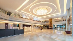 Eine geräumige Lobby mit einem zentralen Kronleuchter, mehreren Etagen und einem Starbucks.