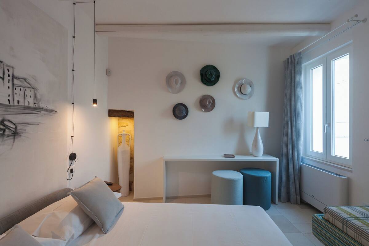 A modern hotel room with a bed, bedside table, lamp, and wall decor.