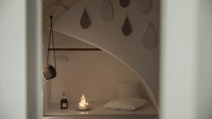 A bedroom with a curved ceiling, a bedside table with candles, a bottle of reed diffuser, and a hanging lamp. - Palazzo Fiscaiolo (Monopoli)