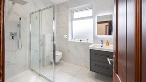 A modern bathroom with a glass shower enclosure, a toilet, a vanity with a mirror, and a window above the sink. - CollegeHouse-FREEParking&HighSpeedWIFI-Modern-Cosy (Whalley Range)
