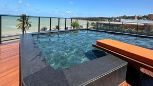 Une piscine aux eaux cristallines, dotée d’une terrasse en bois et offrant une vue sur l’océan.