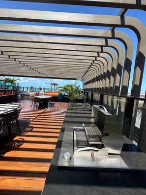 Enjoy al fresco dining with a grill station and comfortable seating under a shaded canopy.