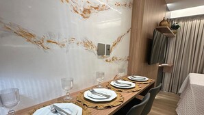 Un espace repas agrémenté d’un mur en marbre, d’une table en bois et de chaises modernes.