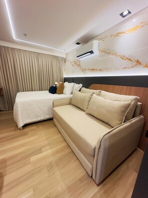 Relax in a spacious room with a large bed, sofa, and wooden headboard.