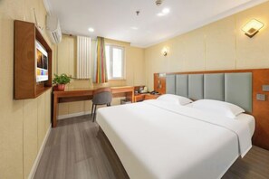 A hotel room with a bed, desk, chair, and a small table.