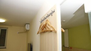 A hotel room with a wooden hanger rack, a flat-screen TV, and a bed with a green wall. - Qiyuan Yueding Business Hotel (Beijing Huilongguan East Street Subway Station) (Beijing)