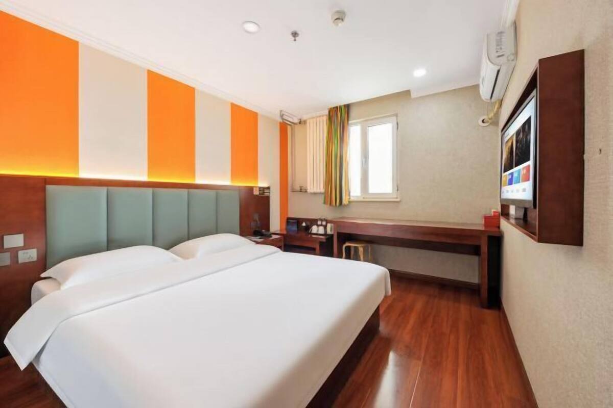 Una habitación de hotel con una cama grande, un escritorio y un ventanal.