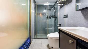 Un baño con cabina de ducha de vidrio, inodoro y lavamanos con armario.