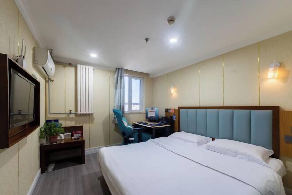 Habitación de hotel con cama, escritorio, silla y televisor.