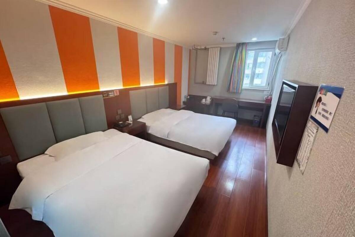 Habitación de hotel con dos camas, un escritorio, una silla y un televisor.