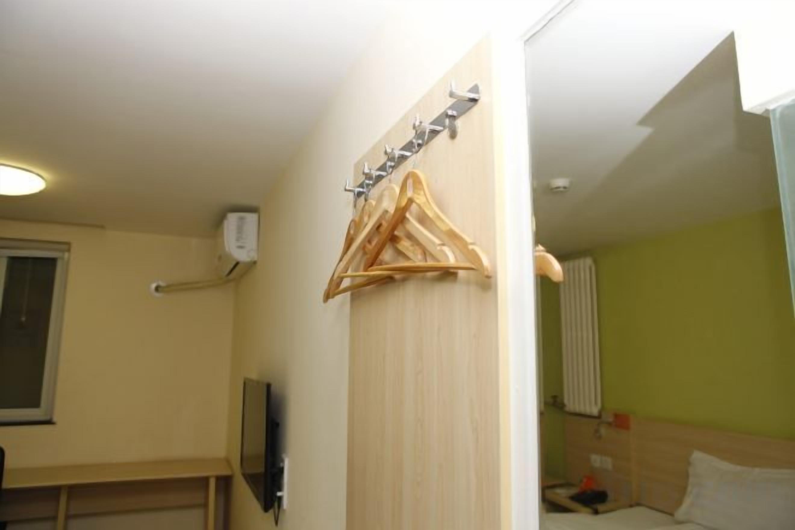 Une chambre d’hôtel avec un lit, un cintre en bois et un téléviseur fixé au mur.