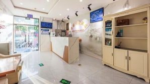 A hotel reception area with a marble floor, a reception desk, and a large cabinet with glass doors. - Qiyuan Yueding Business Hotel (Beijing Huilongguan East Street Subway Station) (Beijing)