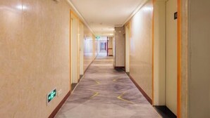 A hotel hallway with marble flooring, doors on both sides, and a visible emergency exit sign. - Qiyuan Yueding Business Hotel (Beijing Huilongguan East Street Subway Station) (Beijing)