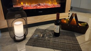 A cozy living room with a fireplace, a lit candle, a wine bottle, and a fruit basket. - Cozy Apartment at Citrus Park (Tampa)