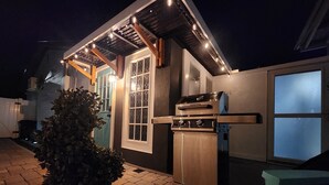 An outdoor kitchen area with a built-in oven and grill, a potted plant, and a wooden bench. - Cozy Apartment at Citrus Park (Tampa)
