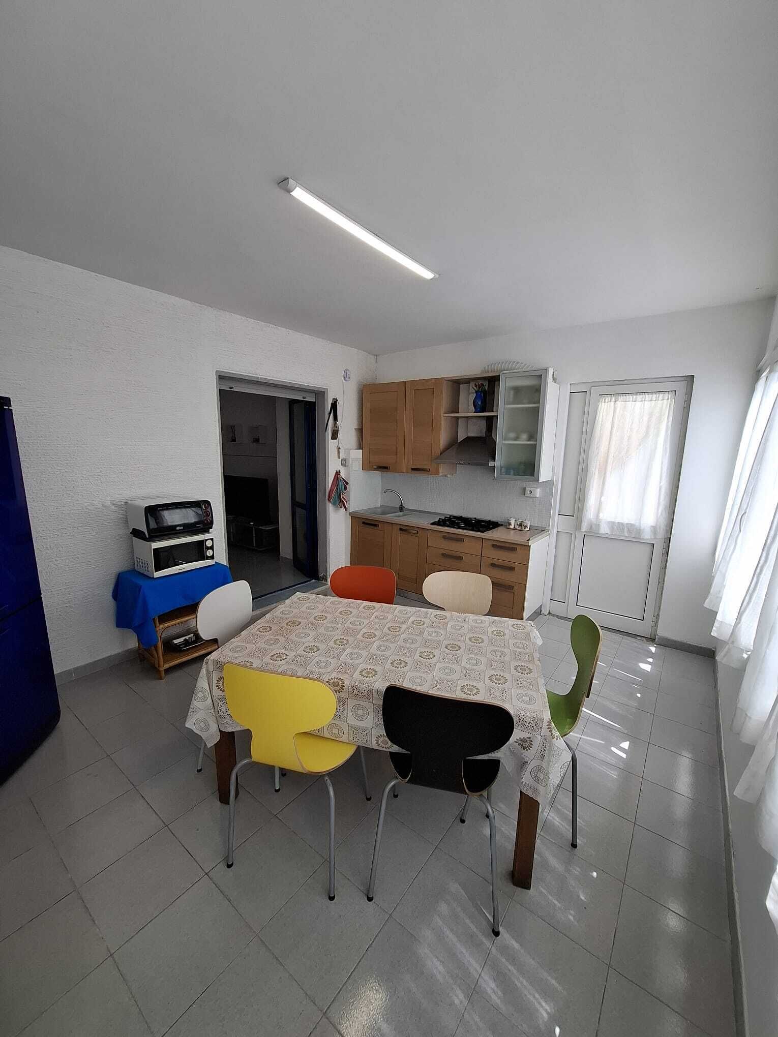 A dining area with a table, chairs, a microwave, and a kitchen in the background.