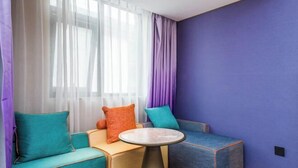 A corner room with a teal sofa, a small round table, and a purple wall. - Manxin Hotel Suzhou Guanqian Street (Suzhou)