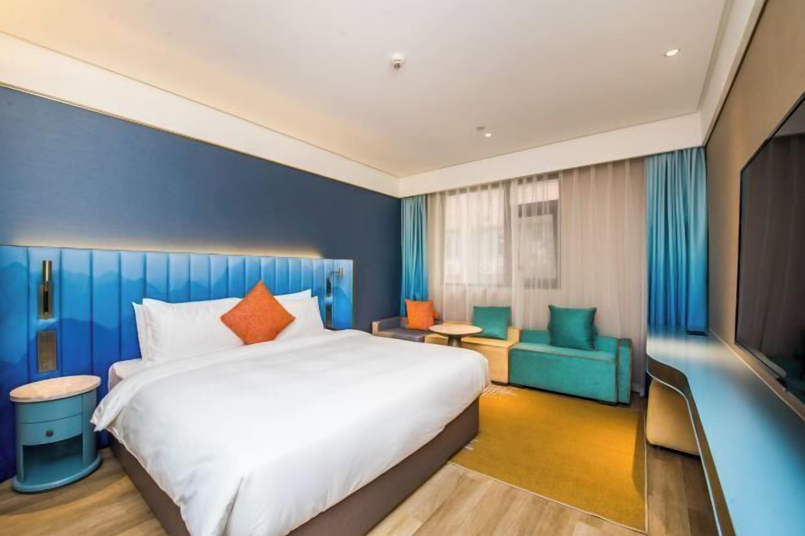 Une chambre d’hôtel avec un grand lit, un canapé, une petite table et un téléviseur.