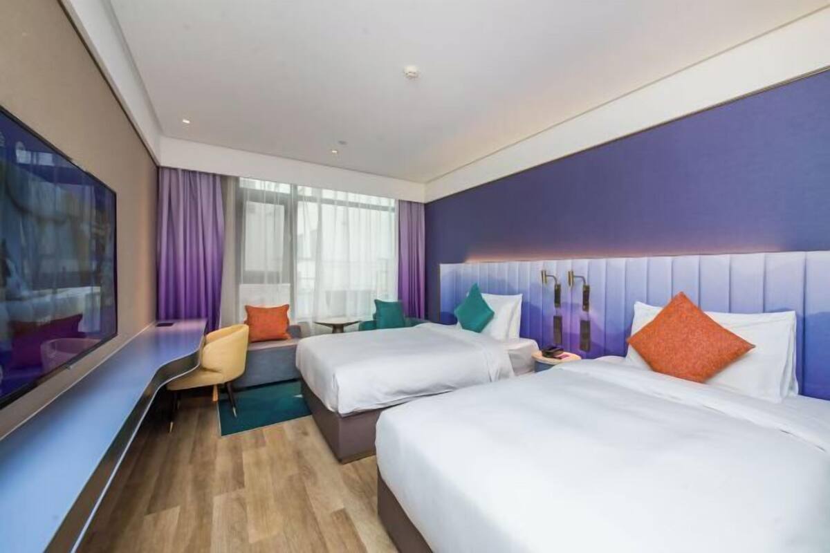 A hotel room with two beds, a seating area, and a large window.