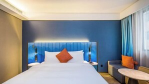 A hotel room with a large bed, a sofa, a small table, and a nightstand. - Manxin Hotel Suzhou Guanqian Street (Suzhou)