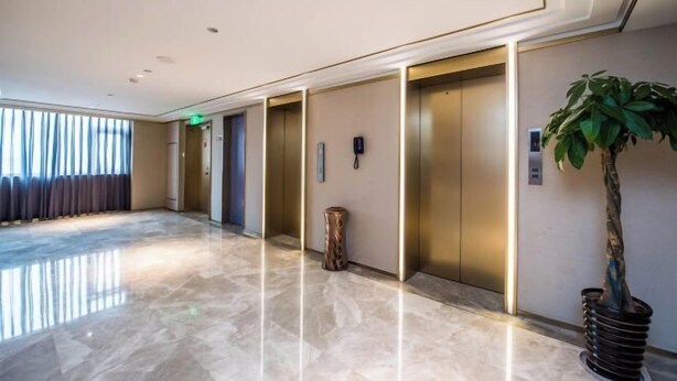 A modern hotel lobby with a marble floor, three elevators, a potted plant, and a large window with curtains. - Manxin Hotel Suzhou Guanqian Street (Suzhou)