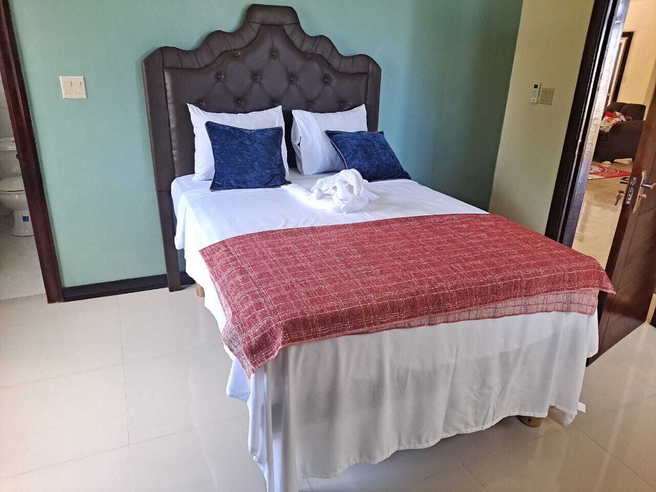 A neatly made bed with a red and white checkered bedspread, two blue pillows, and a white duvet.
