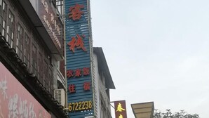 A building with a prominent blue and red signboard displaying the name and contact number of a hotel. - Huangyao Xinyi Inn (Zhaoping)