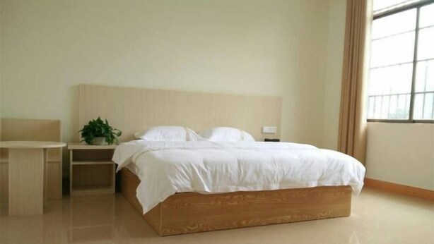 A bedroom with a bed, bedside table, and a potted plant. - Huangyao Xinyi Inn (Zhaoping)