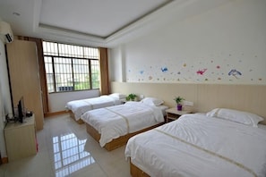 A hotel room with three beds, a desk, a window, and a wall with decorative stickers. - Huangyao Xinyi Inn (Zhaoping)