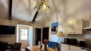 A spacious living area with a wooden dining table, chairs, a sofa, and a kitchen with cabinets and appliances. - Casa Marelina - Fisherman's house in Centuri harbour (Centuri)