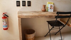 Ein Holztisch mit einem schwarzen Stuhl, einem Feuerlöscher, einem Korbwäscher und einer Vase an der Wand.