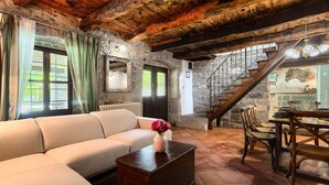 Uma sala de estar acolhedora com sofá, mesa de centro de madeira e um espaço de jantar com cadeiras e mesa.